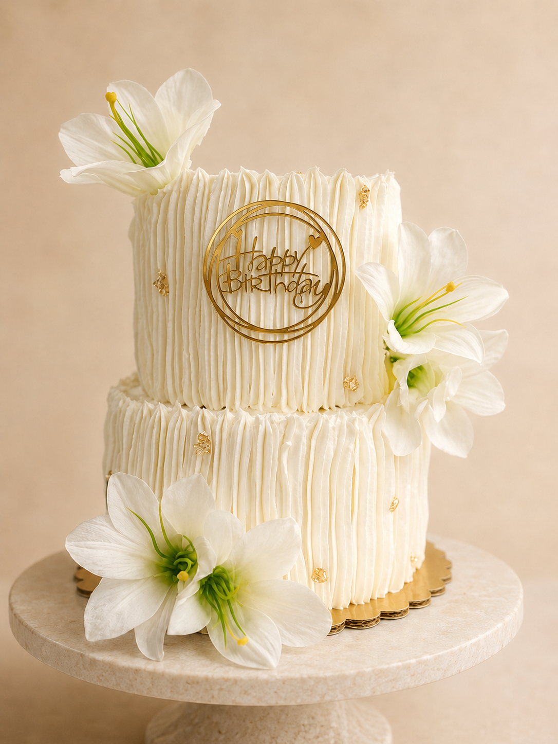 Two-tier white ruffled cake with lilies and gold Happy Birthday topper