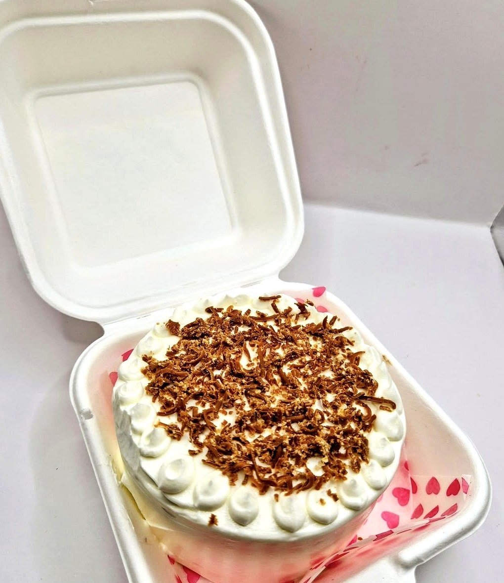Mini bento cake with piped cream and chocolate shavings in a gift box