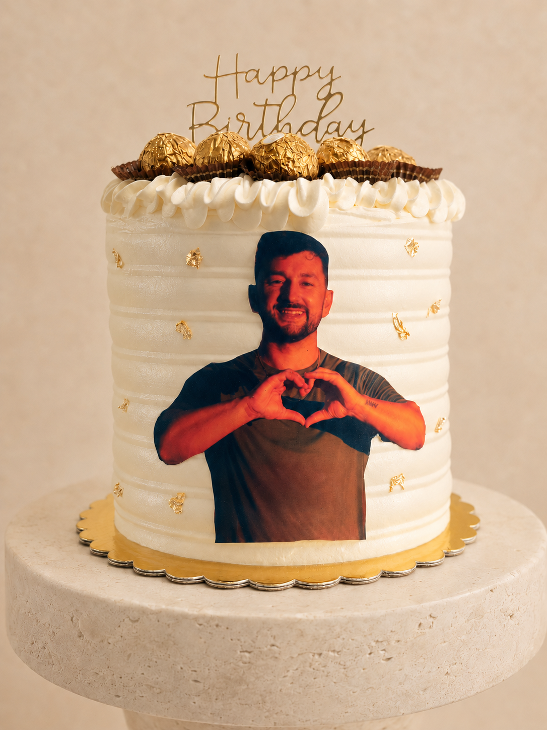 White buttercream birthday cake with a full-color photo print, gold leaf flecks and Ferrero Rocher chocolates on top
