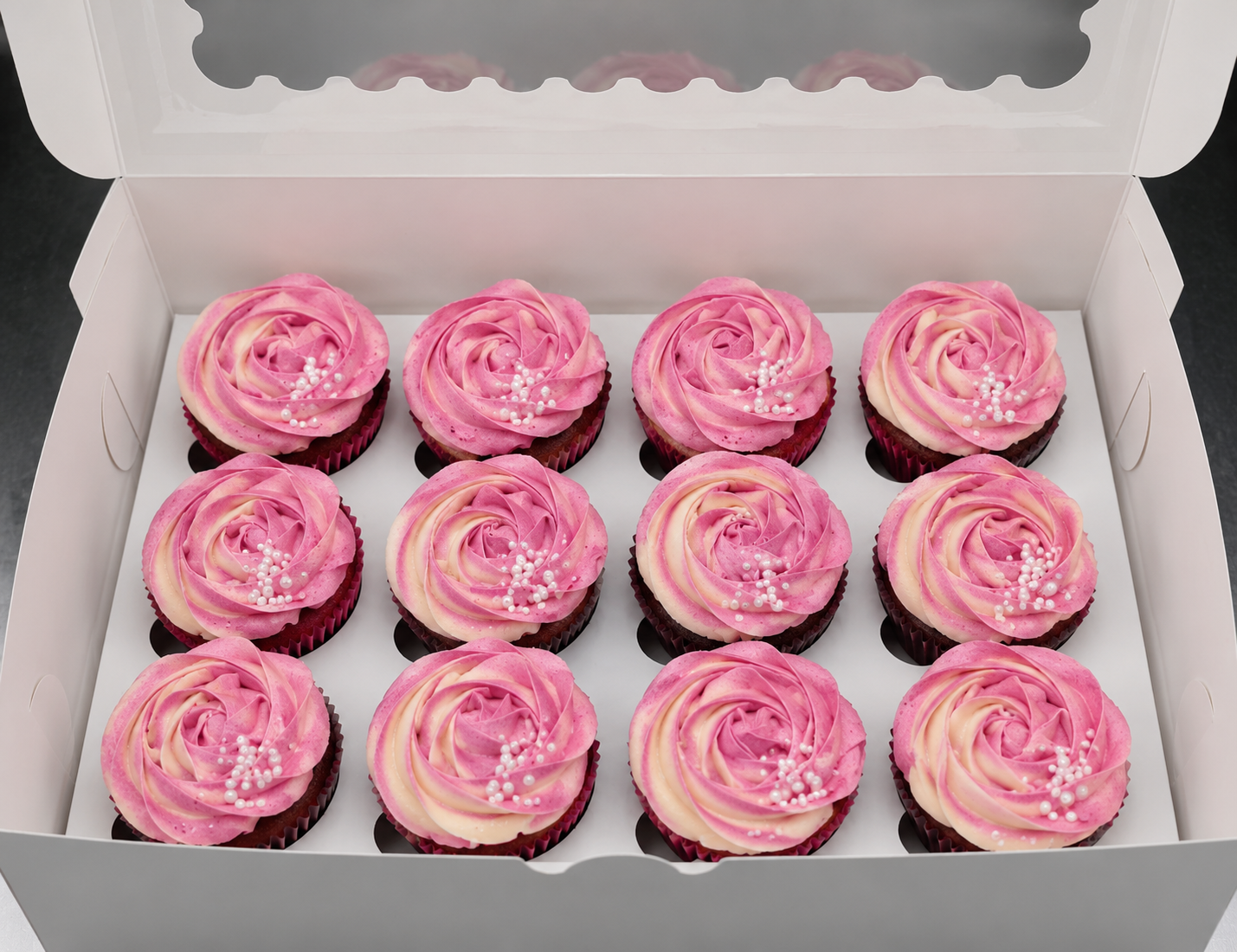 Boxed dozen of red velvet cupcakes with pink and cream two-tone rose swirl buttercream and white sugar pearls